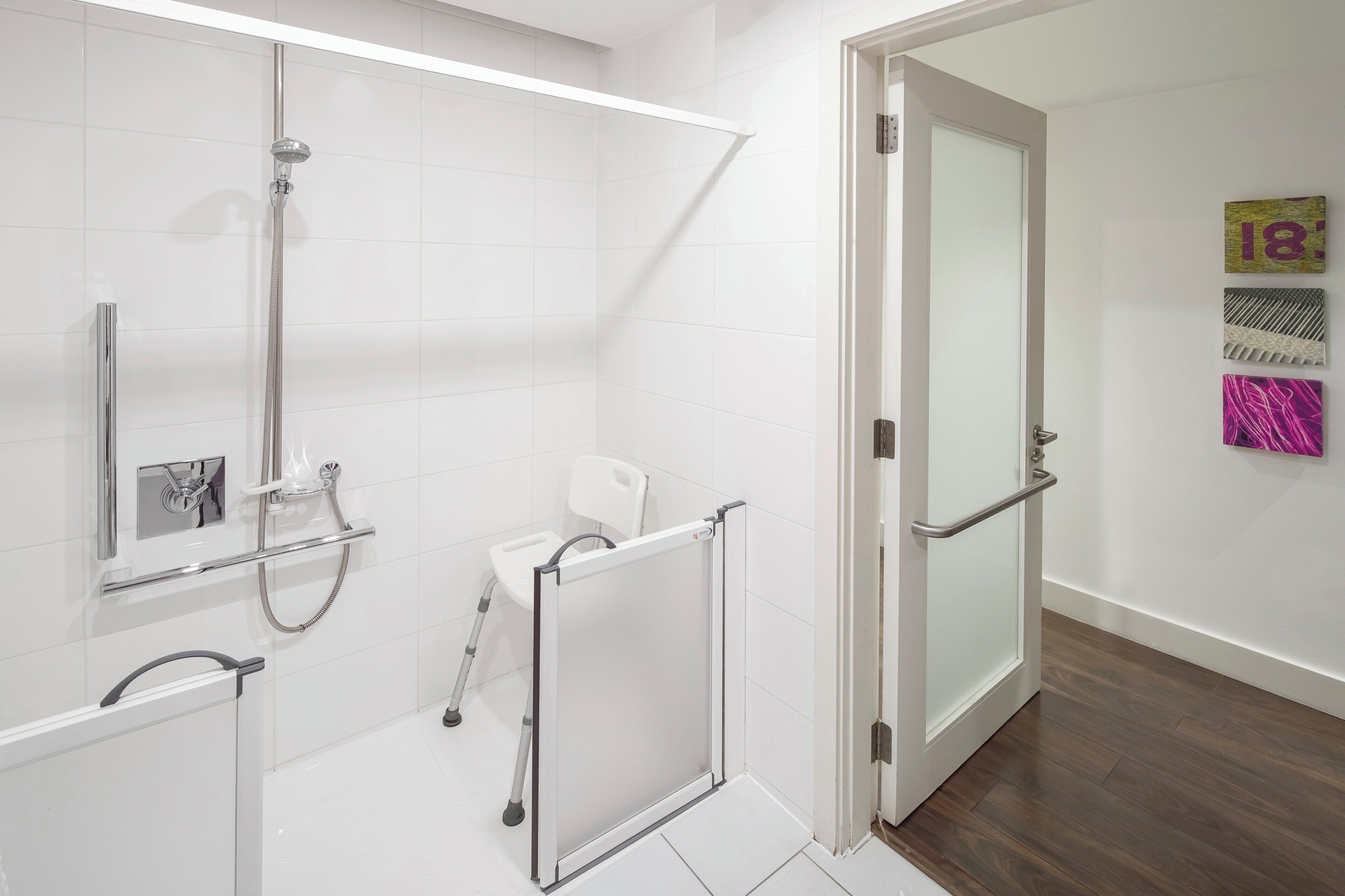 Un baño moderno con ducha, inodoro y una puerta de vidrio que da a otra habitación.