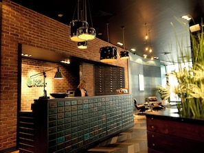 Un espace bar avec un mur en briques, un comptoir doté d’une caisse enregistreuse et une série de tiroirs en dessous.
