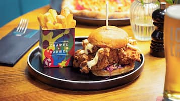 A meal with a chicken sandwich, fries, and a pizza on a wooden table.