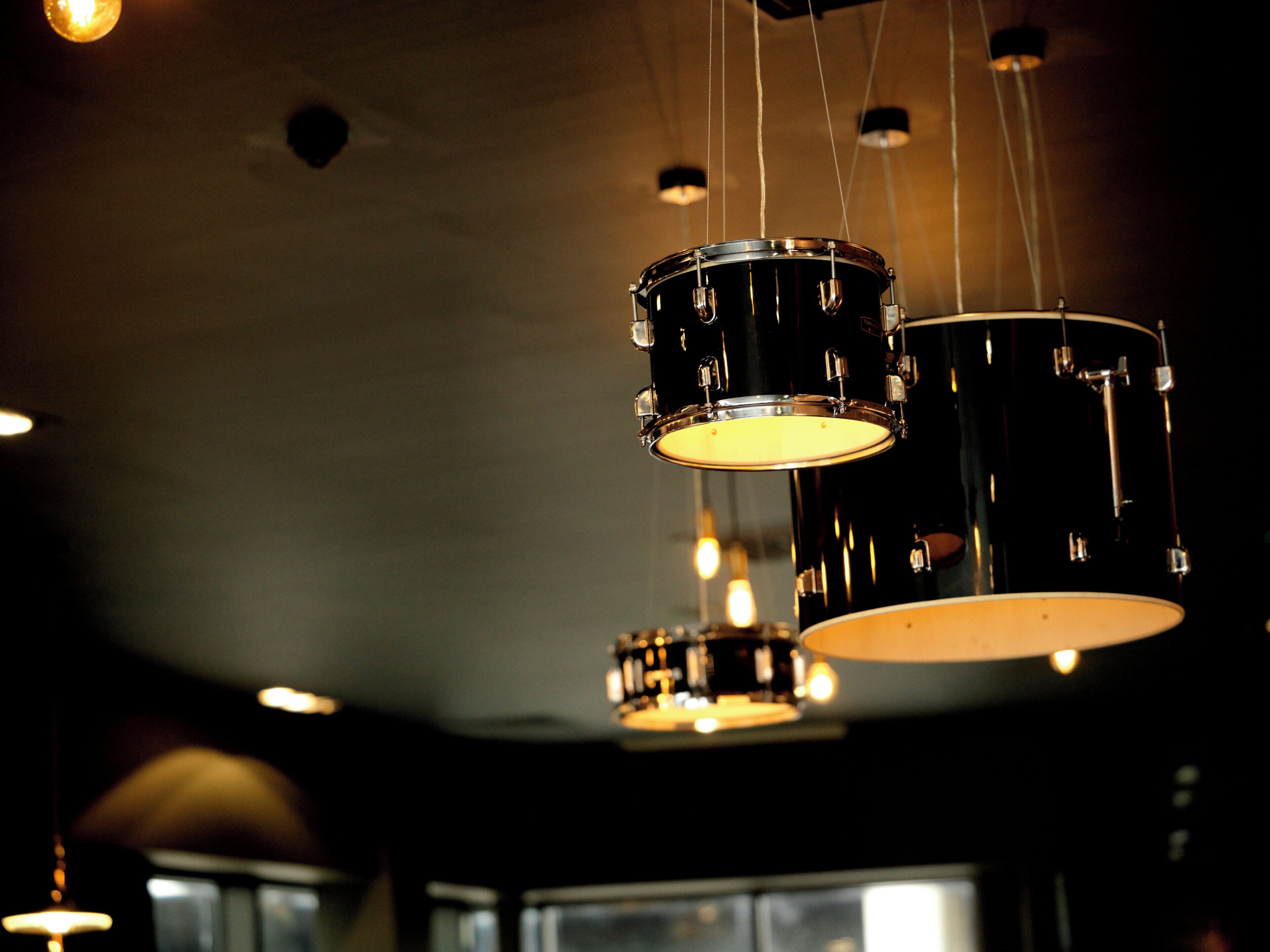 A drum set with hanging lights in a dimly lit room.