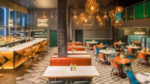 A bar area with a neon sign, multiple seating options including booths and tables, and a patterned floor.