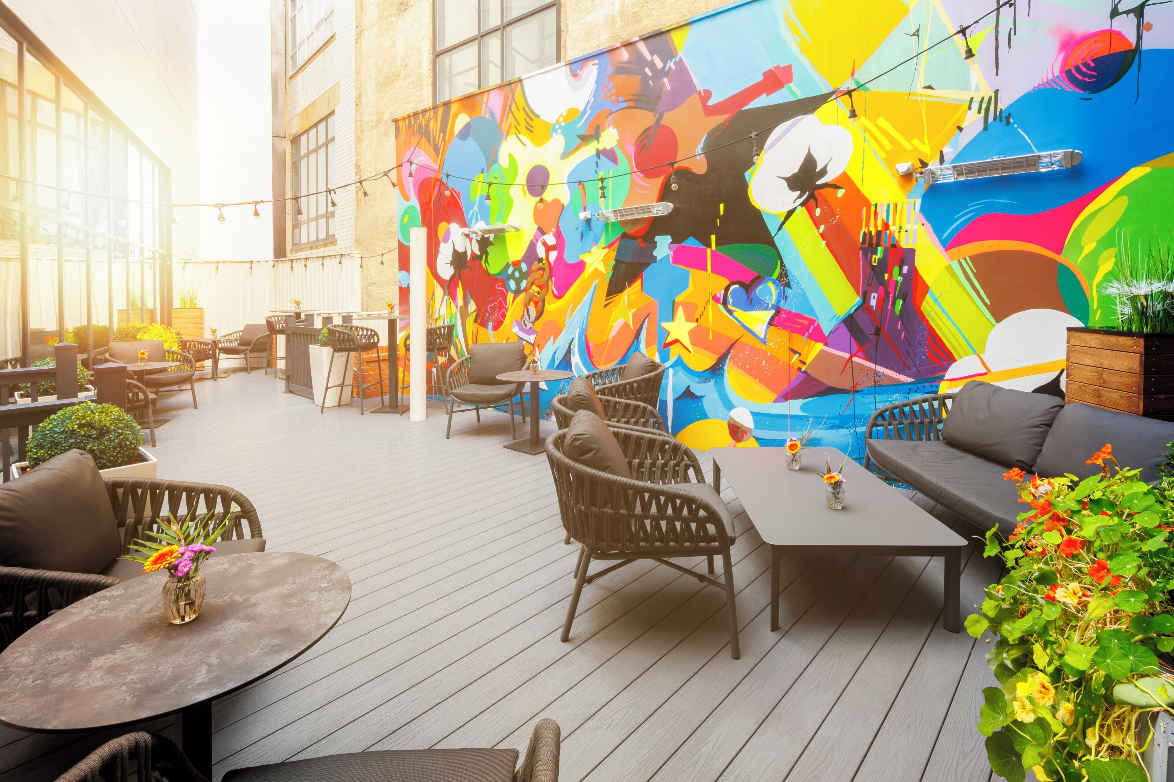 An outdoor patio with wicker furniture, a mural, and a pool.
