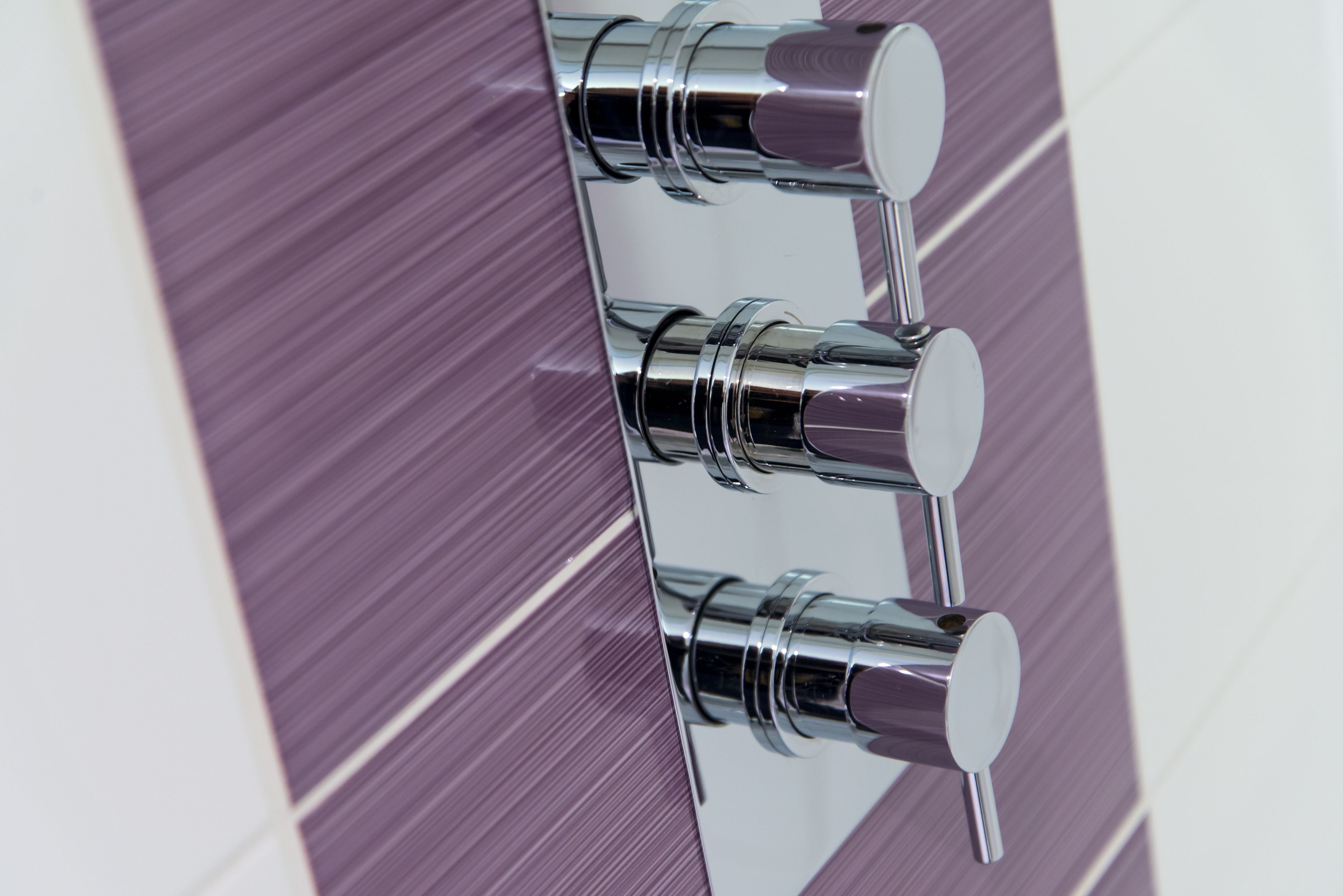 Une salle de bain avec un miroir et trois robinets chromés.