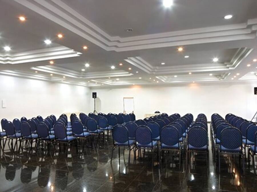 A conference room with rows of blue chairs, a polished black floor, and recessed ceiling lighting.