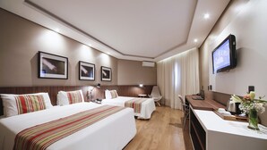 A hotel room with two beds, a desk, a TV, and a window with curtains. - Grand Hotel Royal Sorocaba by Atlantica (Sorocaba)
