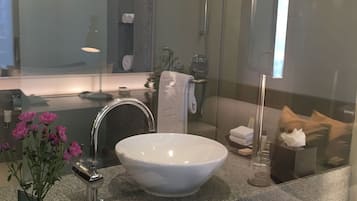 Un baño moderno con un lavamanos grande de color blanco, encimera de granito y cabina de ducha con mampara de vidrio.