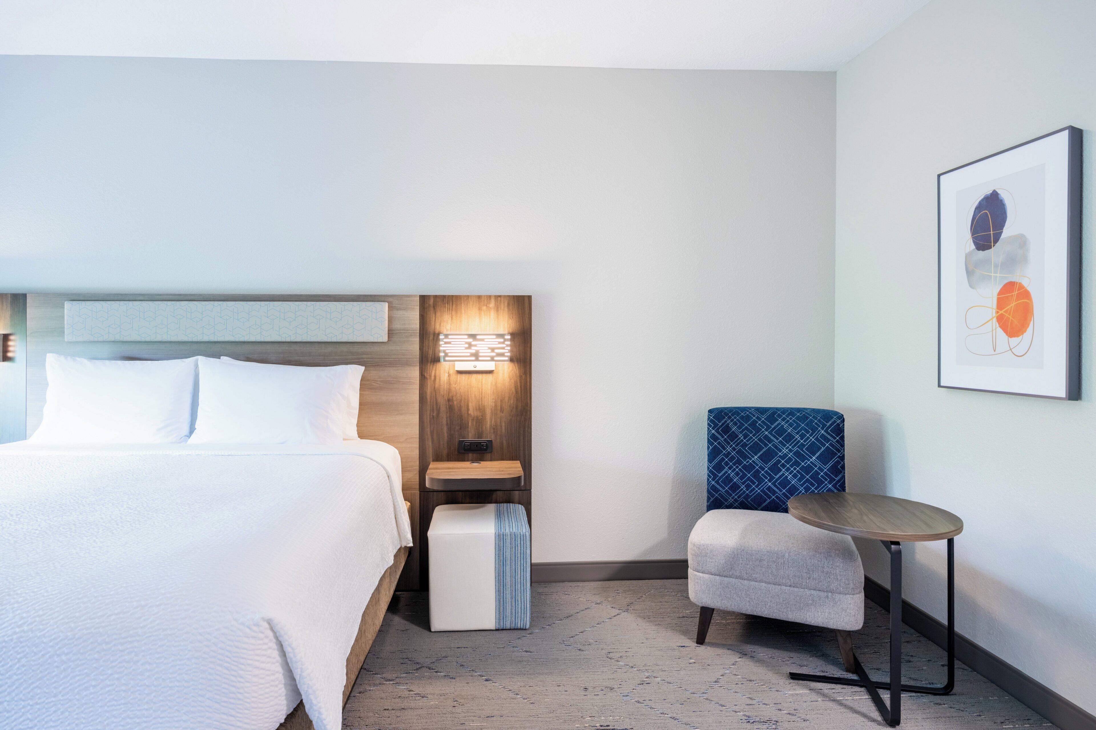Ein Hotelzimmer mit Bett, Nachttisch, Schreibtisch und Stuhl.