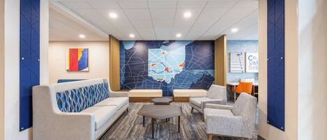 A lobby with a sofa, chairs, a coffee table, a map mural, and a sign reading 'COLUMBUS BUS'.