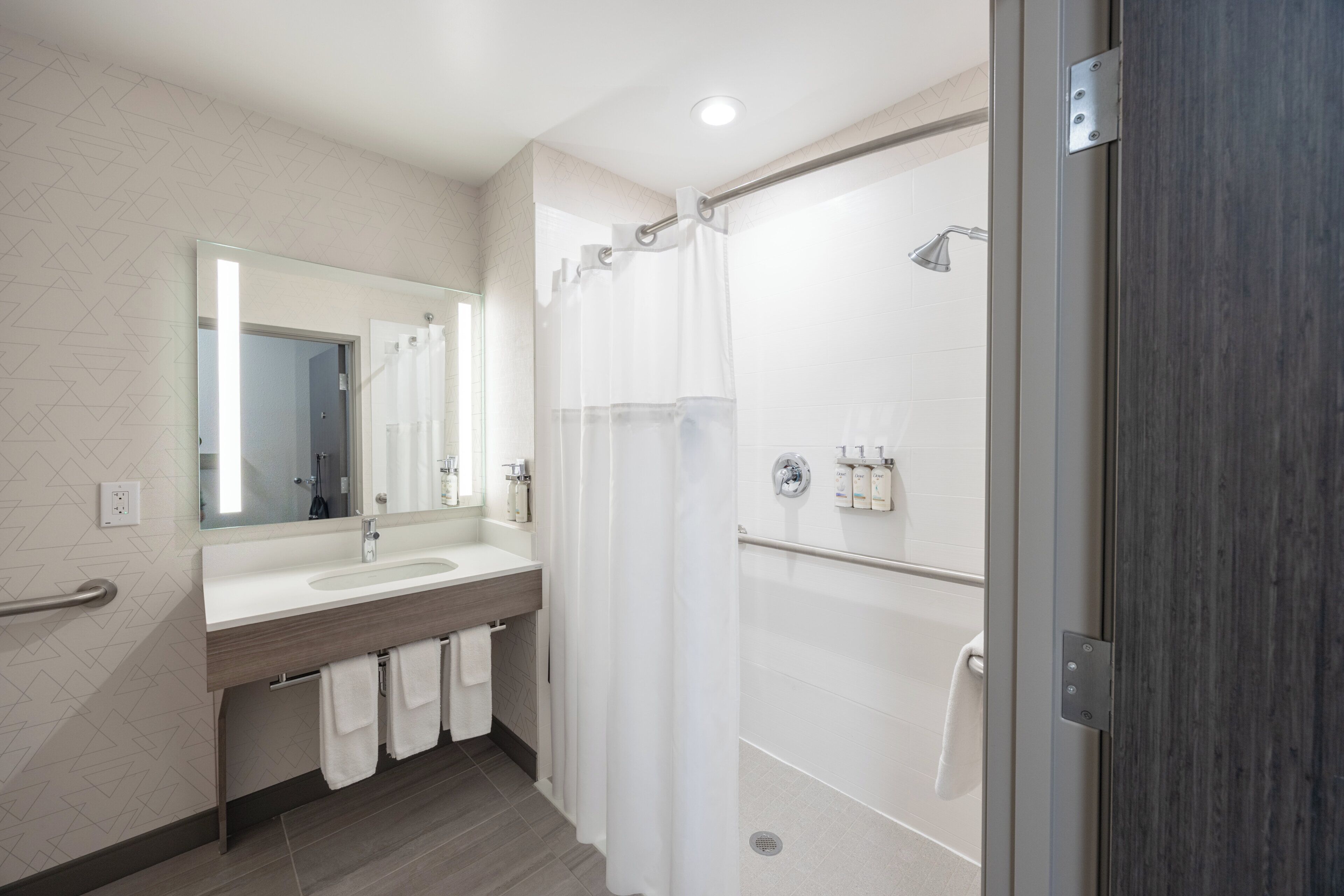 A modern bathroom with a shower, a sink, and a mirror.
