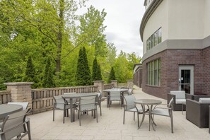 An outdoor patio with tables and chairs, surrounded by a brick wall and trees. - Holiday Inn Express Hotels & Suites Columbus-Polaris Parkway by IHG (Columbus)