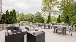 Un espace extérieur aménagé en terrasse, avec des meubles en osier, des tables et des chaises.