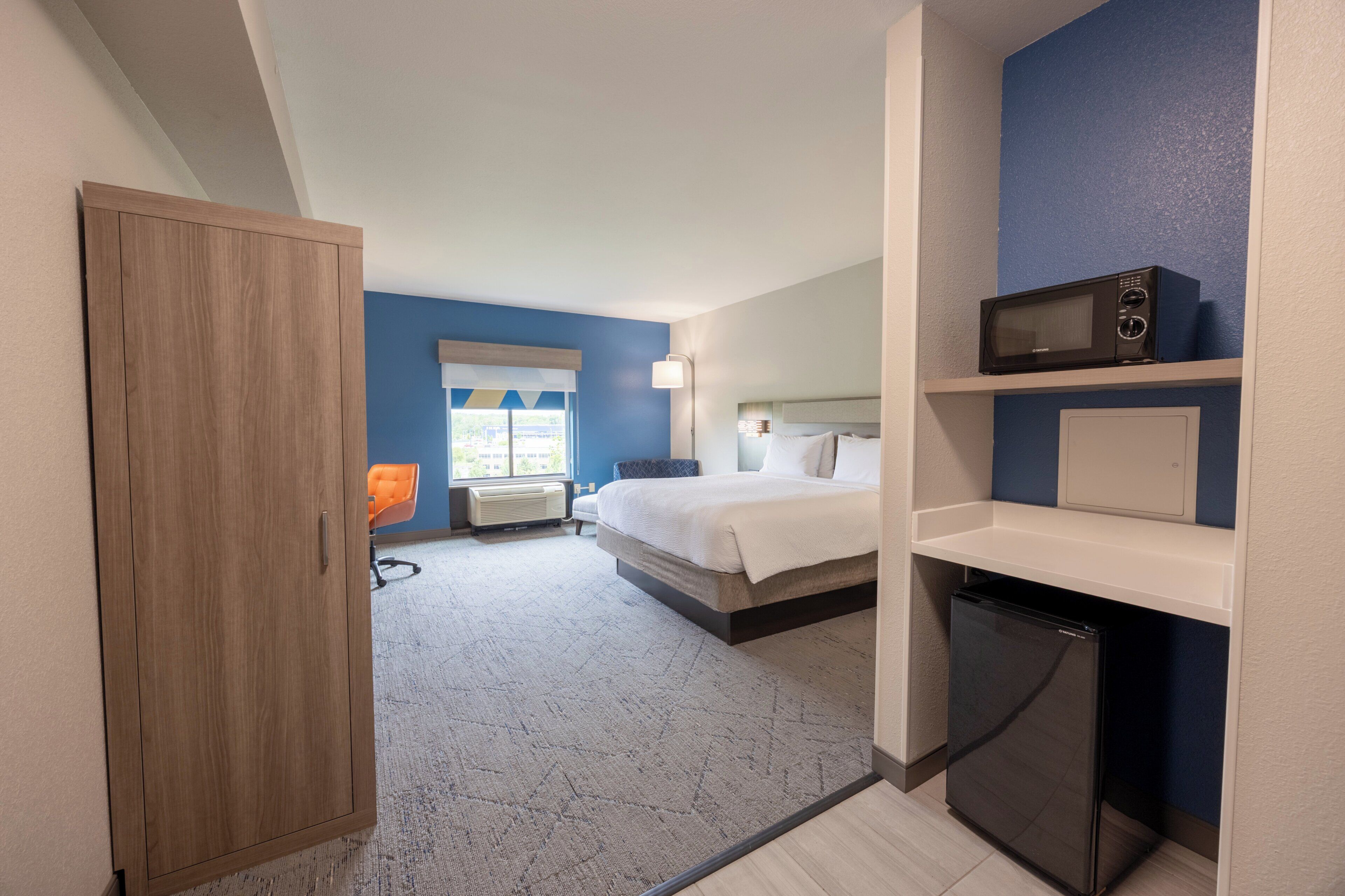 Ein Hotelzimmer mit einem Bett, einem Schreibtisch, einer Mikrowelle und einem Kühlschrank.