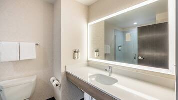 A modern bathroom with a white sink, a large mirror, and a toilet.
