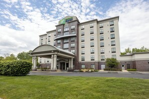 A hotel with a central entrance, multiple floors, and a parking lot.