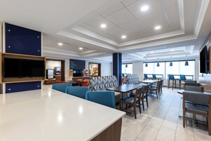 A modern restaurant with high ceilings, recessed lighting, and a variety of seating options including booths and tables.