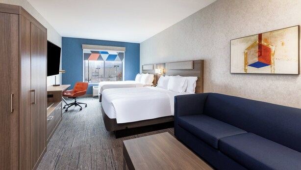 Una habitación de hotel con una cama grande, un sofá, un escritorio con una silla y un televisor.