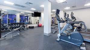Une salle de sport équipée de machines de cardio, de bancs de musculation et d’haltères.