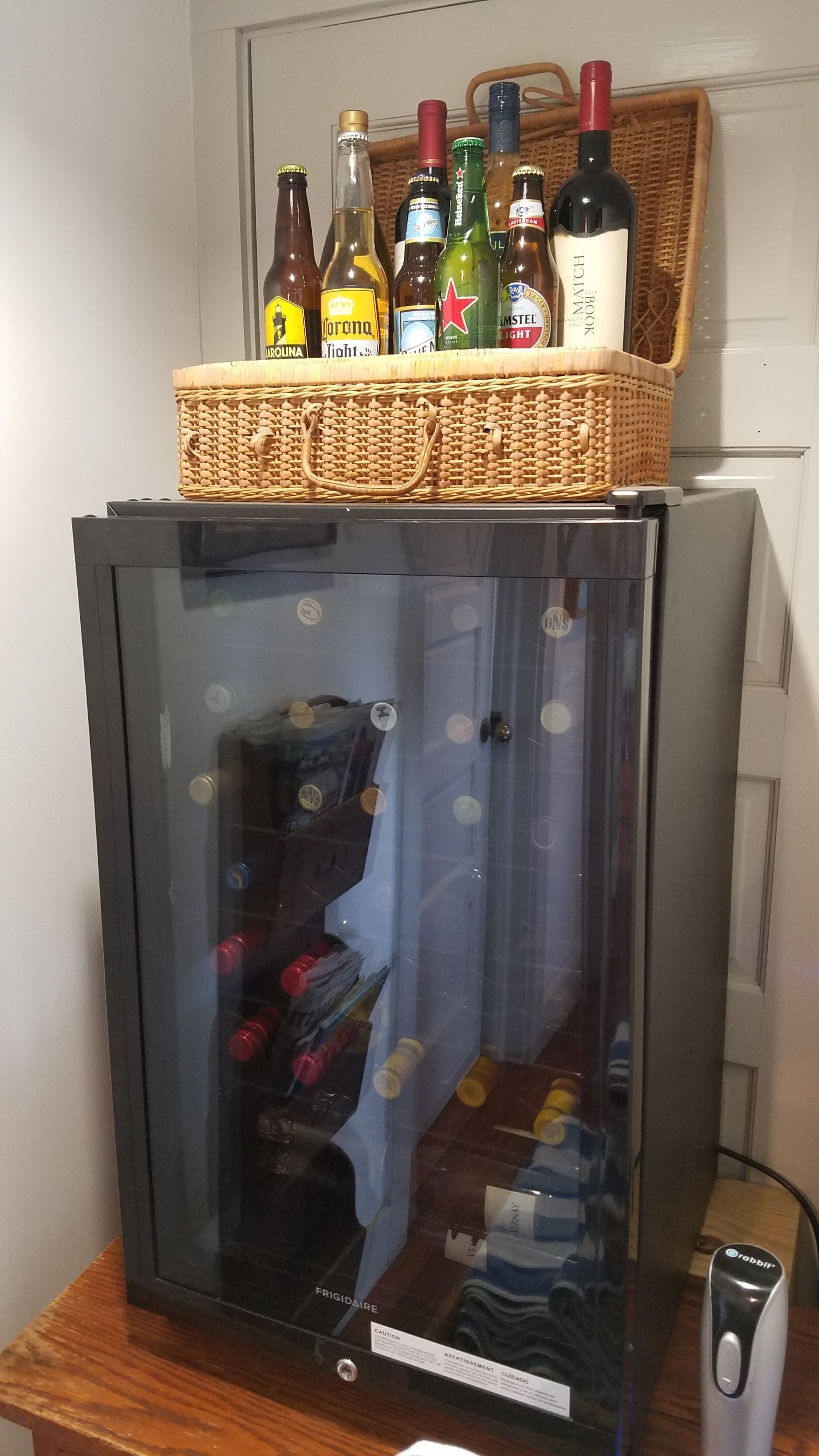 A refrigerator with a basket of beer bottles on top.