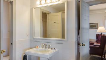 Une salle de bain avec un lavabo blanc, un miroir et une porte de douche.