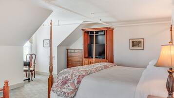 Un dormitorio con una cama grande, un armario de madera, un televisor y un escritorio con una silla.