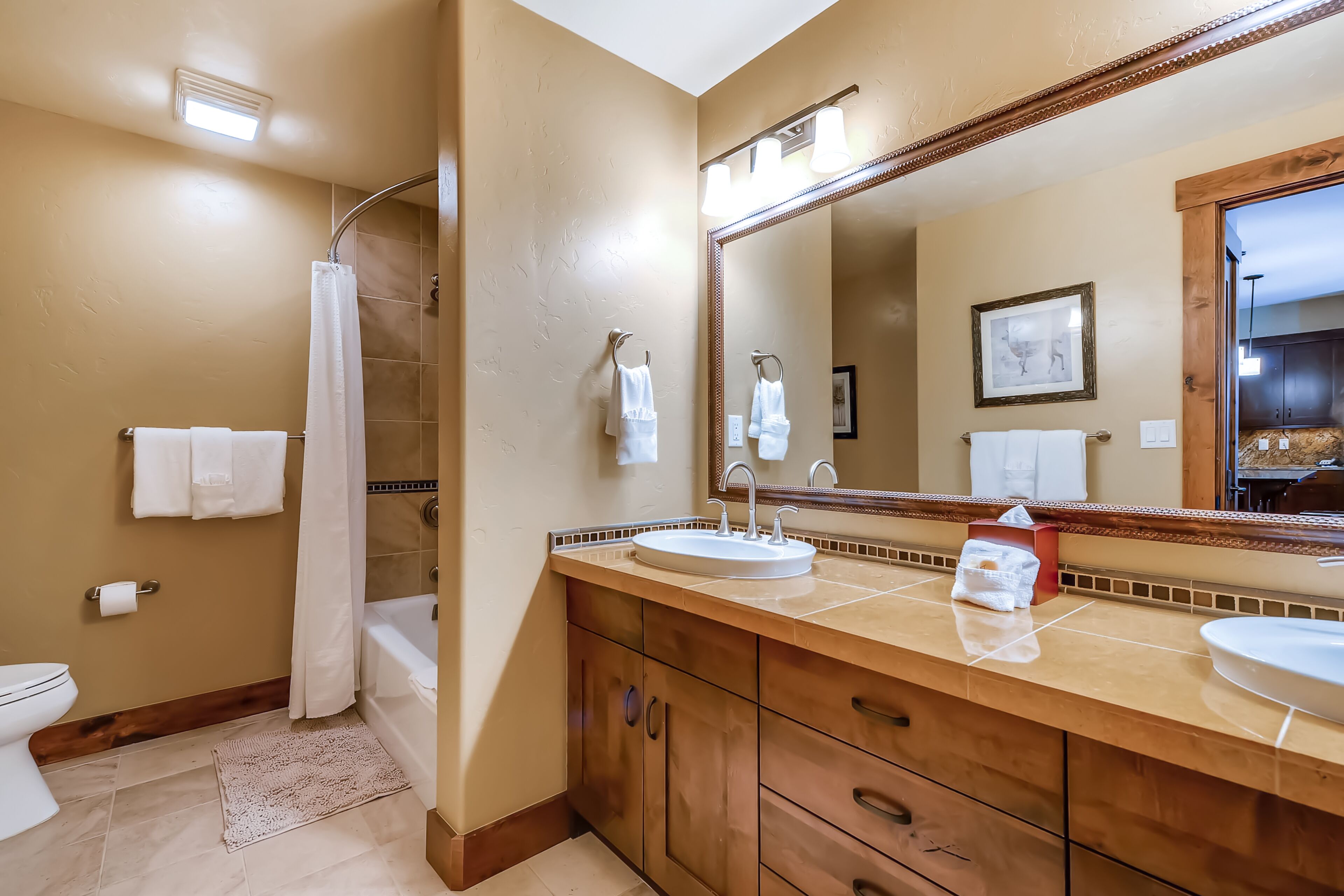 Une salle de bain avec une douche, deux lavabos, un grand miroir et des meubles en bois.