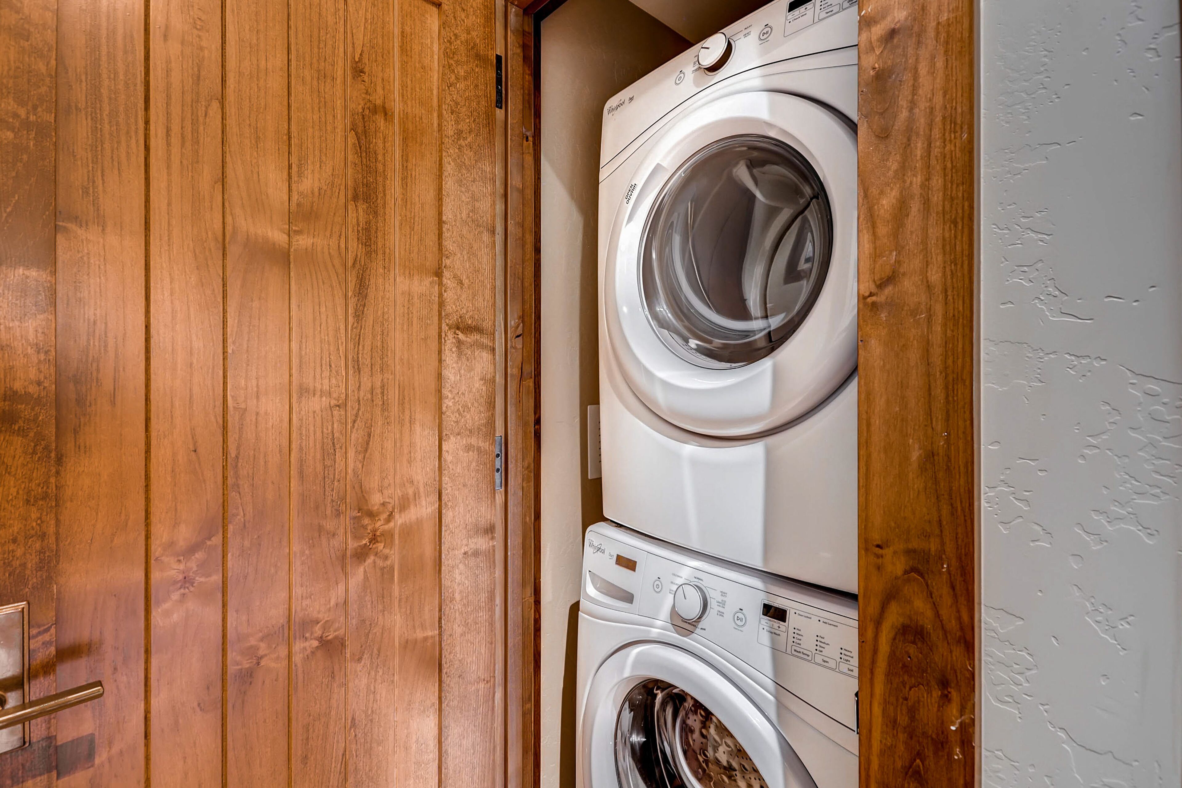 Puerta de madera que da a un cuarto de lavado con lavadoras apiladas.