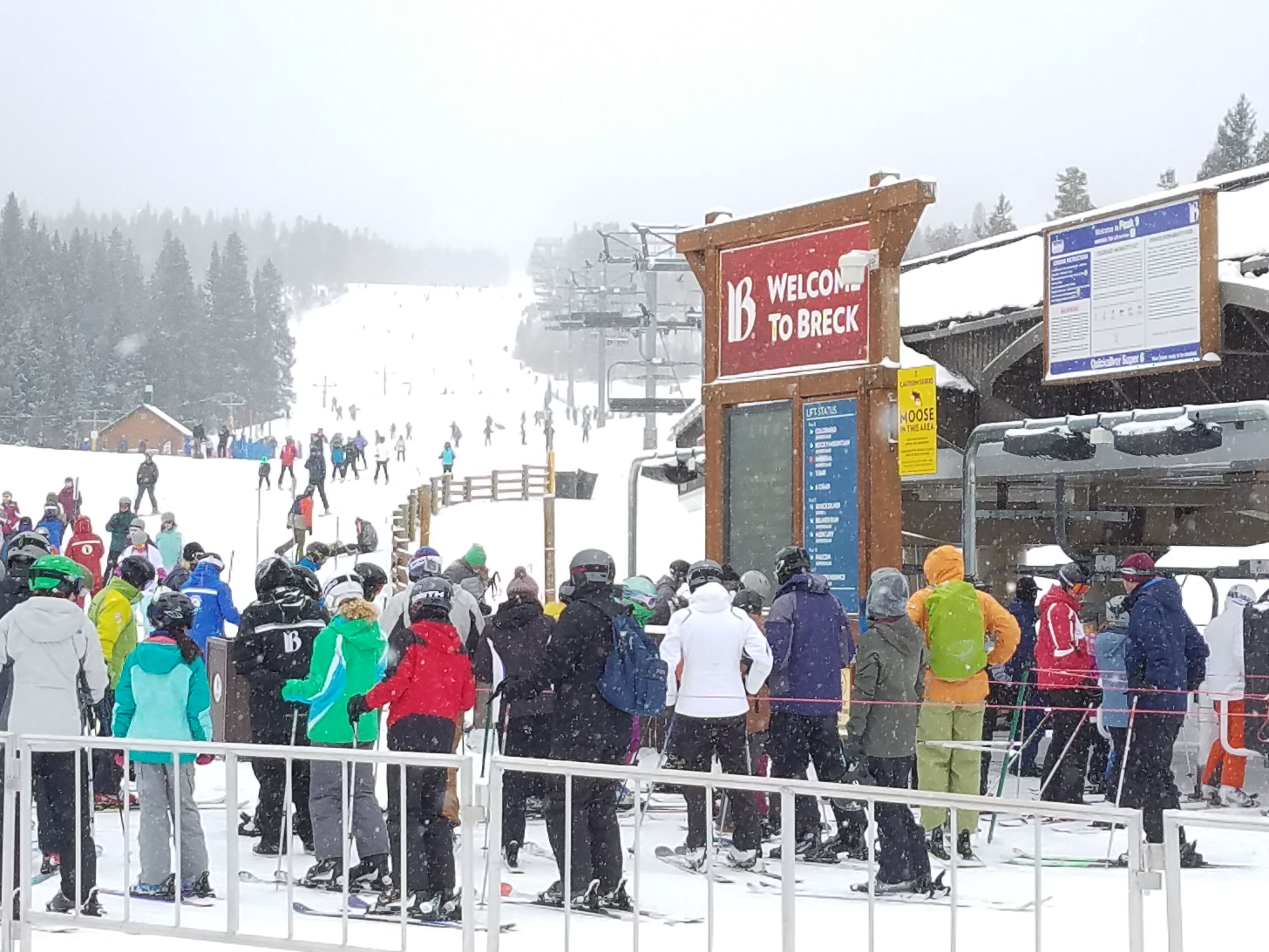 A ski lift station with a 'Welcome to Breck' sign, a lift status board, and a snowy landscape in the background.