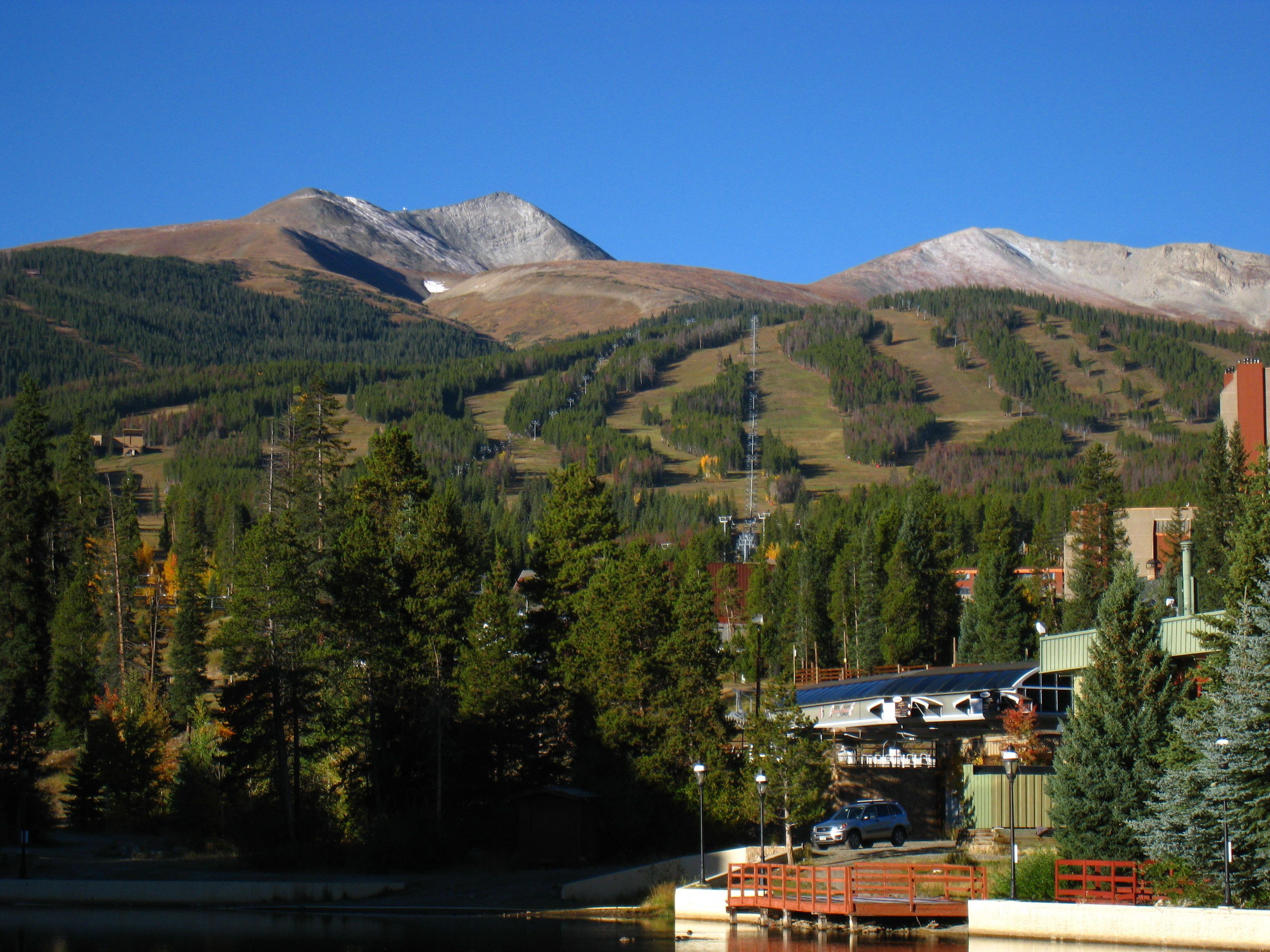 A mountain landscape with a lake, a bridge, and buildings with a view of the mountains.