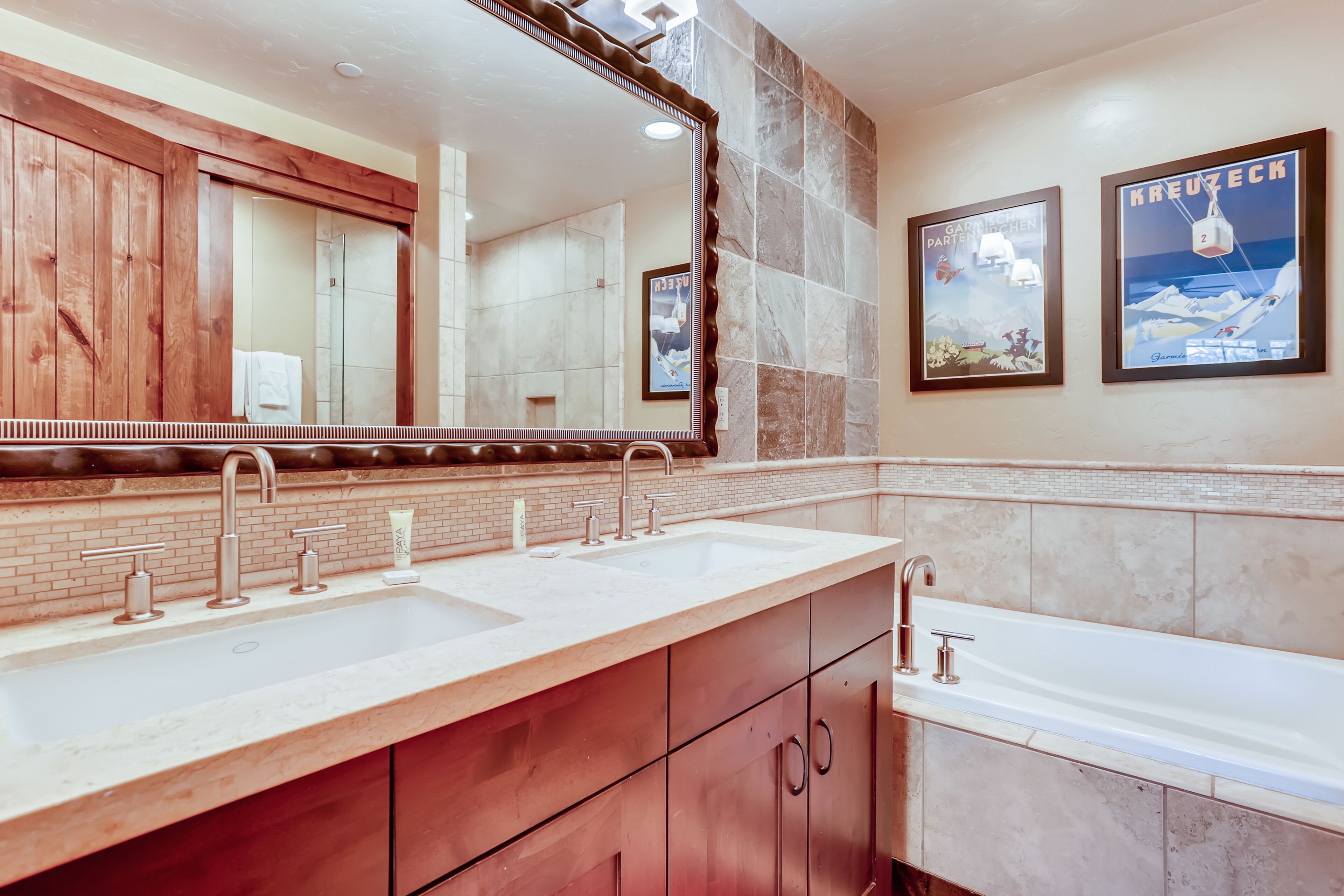 A bathroom with a double sink, wooden vanity, and a large mirror.