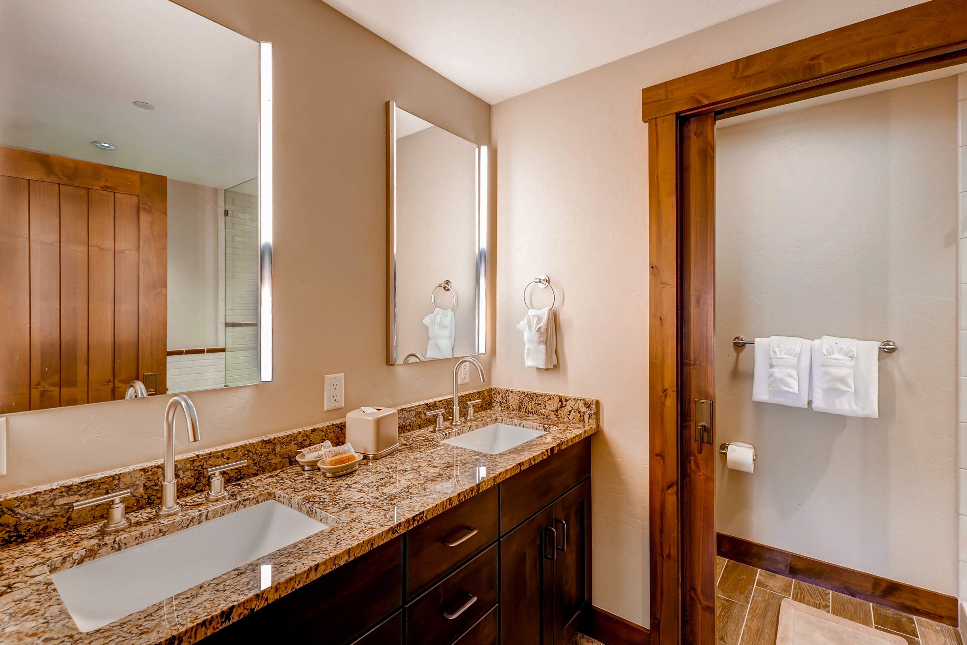 Une salle de bain avec un double lavabo, un grand miroir, des meubles en bois et un porte-serviettes.