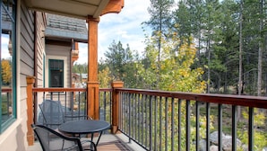 A wooden deck with a table and chairs, overlooking a forested area with autumn foliage. - Water House on Main Street (Breckenridge)