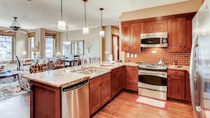 A spacious kitchen with wooden cabinets, stainless steel appliances, and a large island with a dishwasher. - Water House on Main Street (Breckenridge)