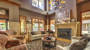 A spacious living room with leather sofas, a fireplace, and a large window overlooking a parking area. - Water House on Main Street (Breckenridge)