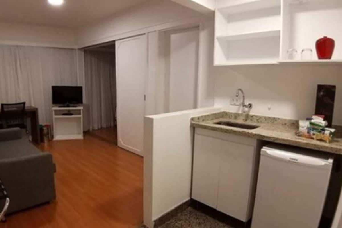 A compact living space with a kitchenette, a sofa, and a television in the living area.