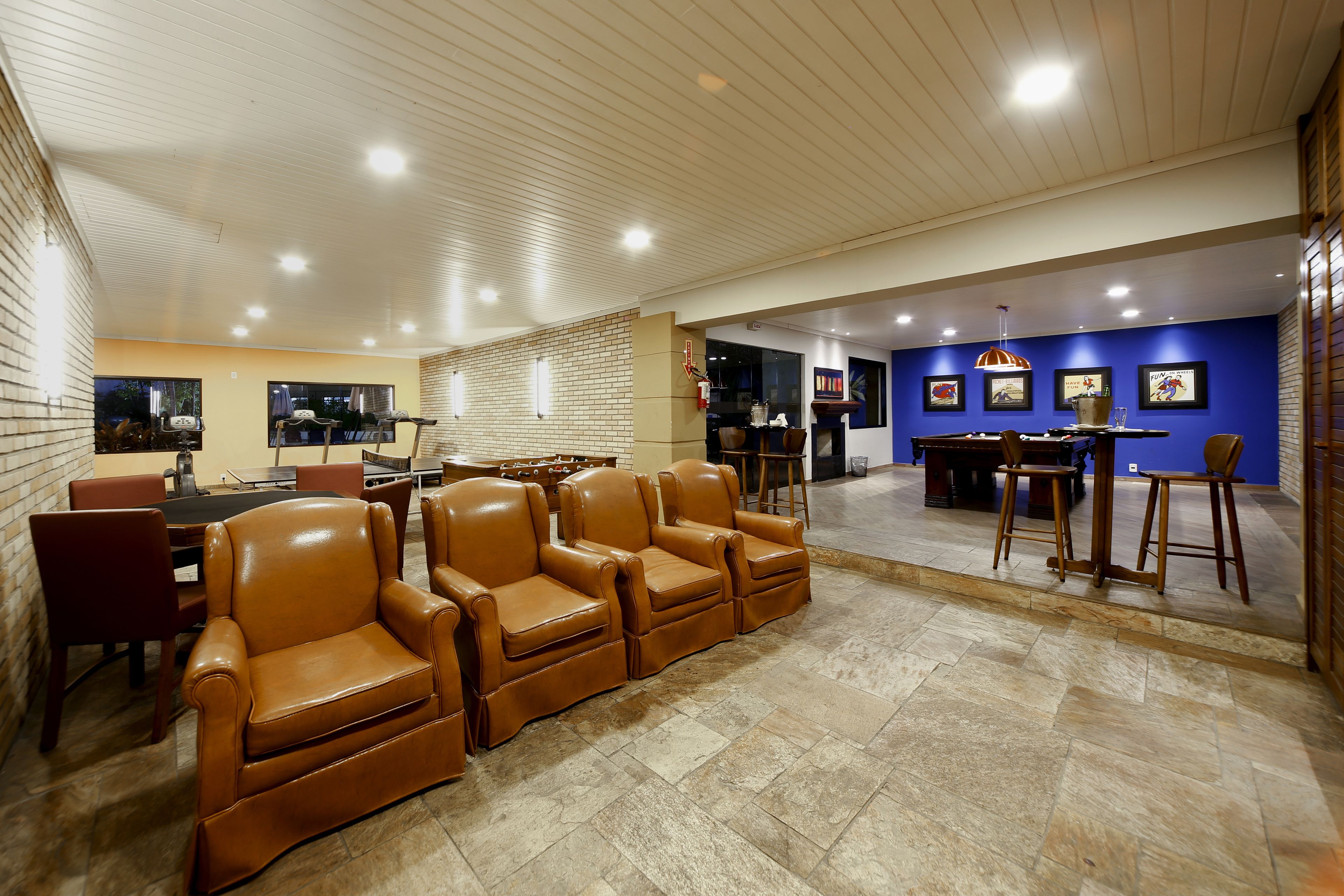 A spacious indoor area with leather sofas, a dining table, and a bar area with stools.