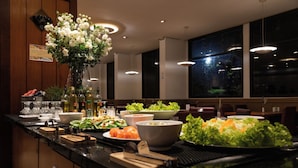 A buffet setup with various dishes, a vase of flowers, and a sign on the wall.