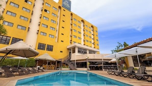 A hotel with a swimming pool, outdoor seating, and a yellow facade.