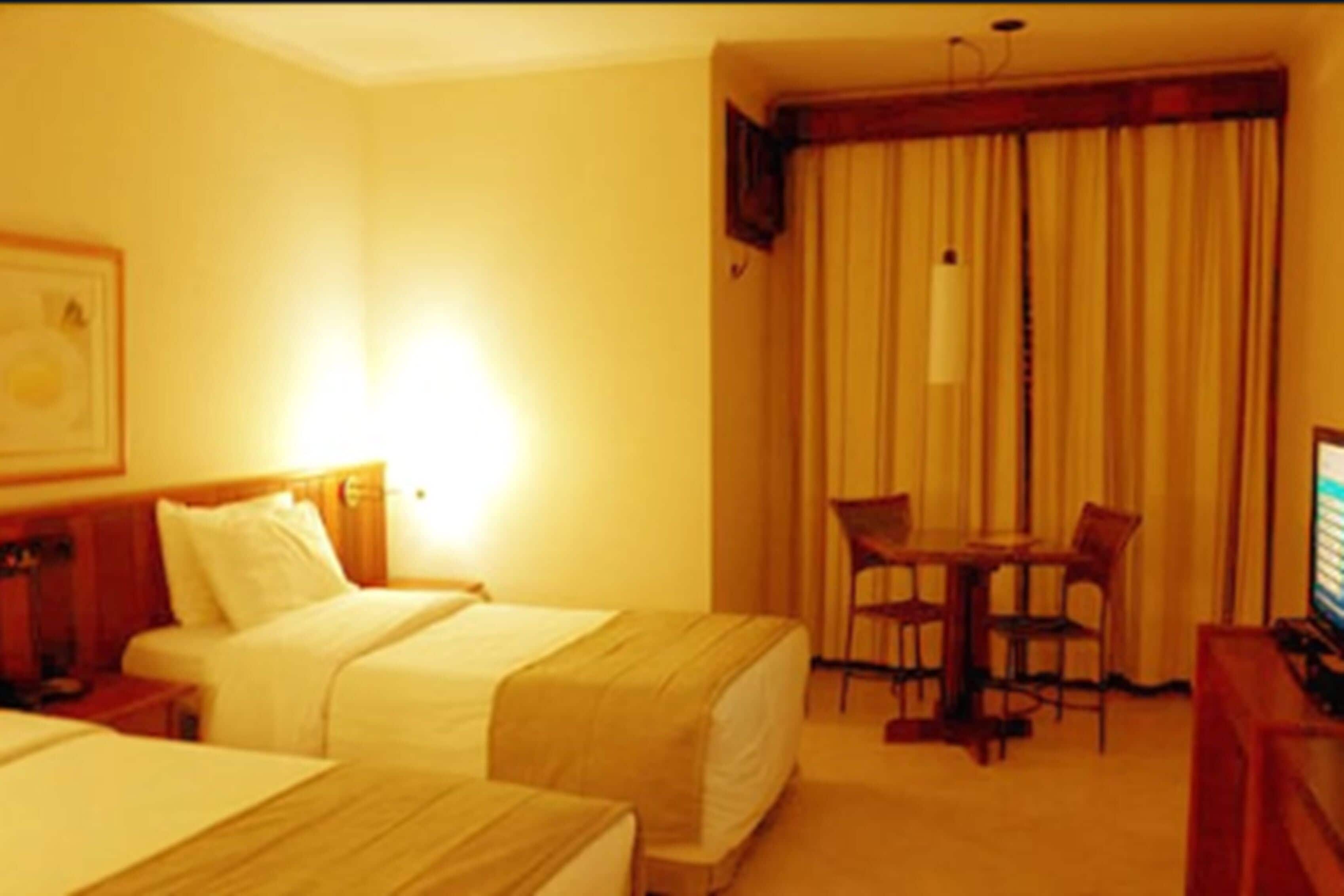 Habitación de hotel con dos camas, un escritorio y televisión.