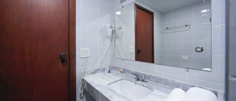 Un baño con puerta de madera, lavamanos de mármol, un espejo y un perchero para toallas.