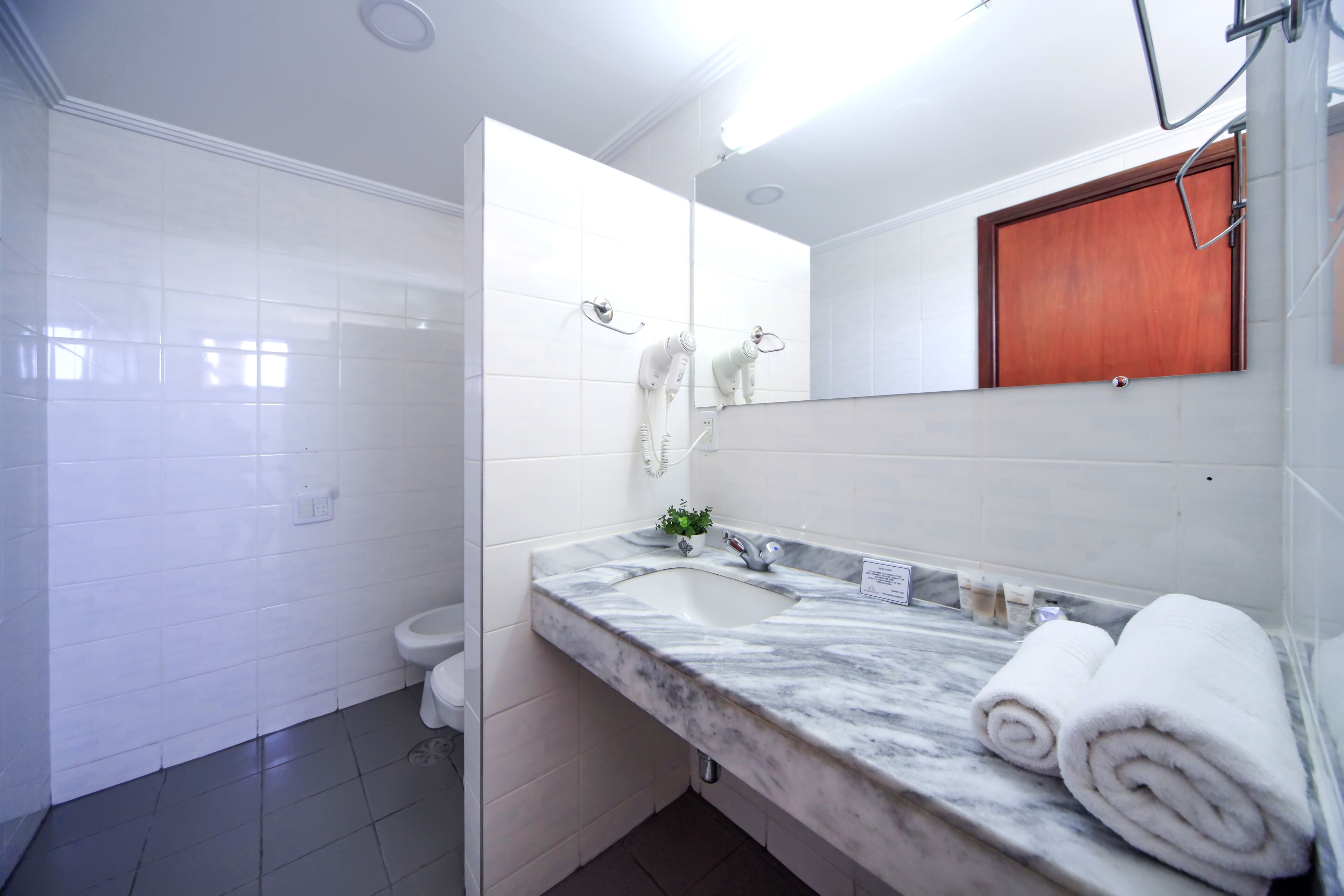 A modern bathroom with a marble sink, a toilet, and a mirror.