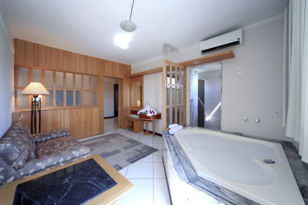 Une salle de bain moderne avec une grande baignoire, un meuble-lavabo en bois et un canapé.
