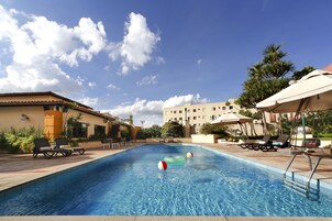 Una piscina al aire libre, sombrillas, sillones reclinables de piscina