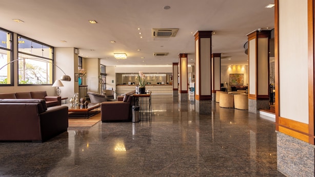 A spacious lobby with a polished marble floor, leather seating, and large windows offering natural light.