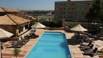 Una piscina al aire libre, sombrillas, sillones reclinables de piscina