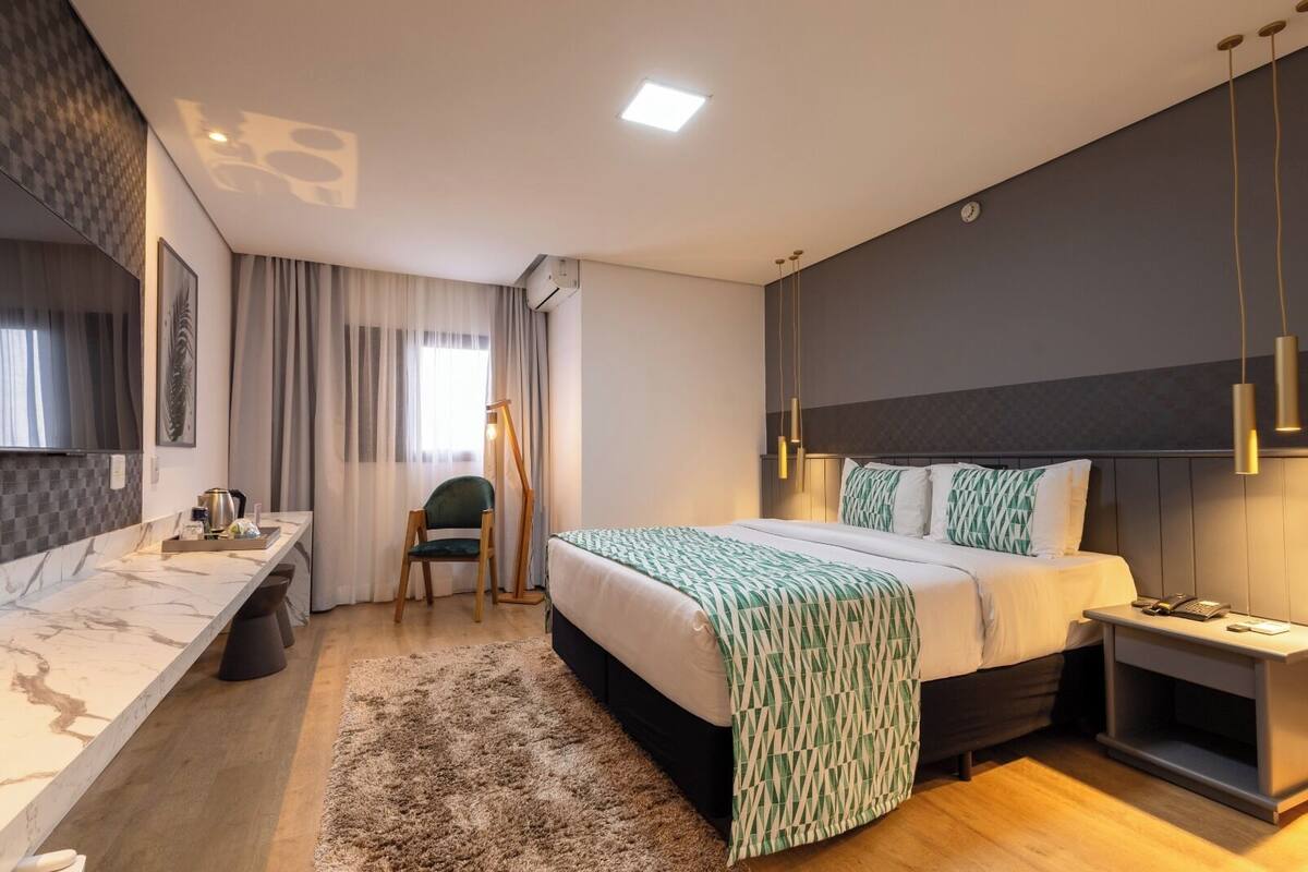 Une chambre d’hôtel moderne, dotée d’un grand lit, d’une table de chevet et d’un bureau avec une chaise.