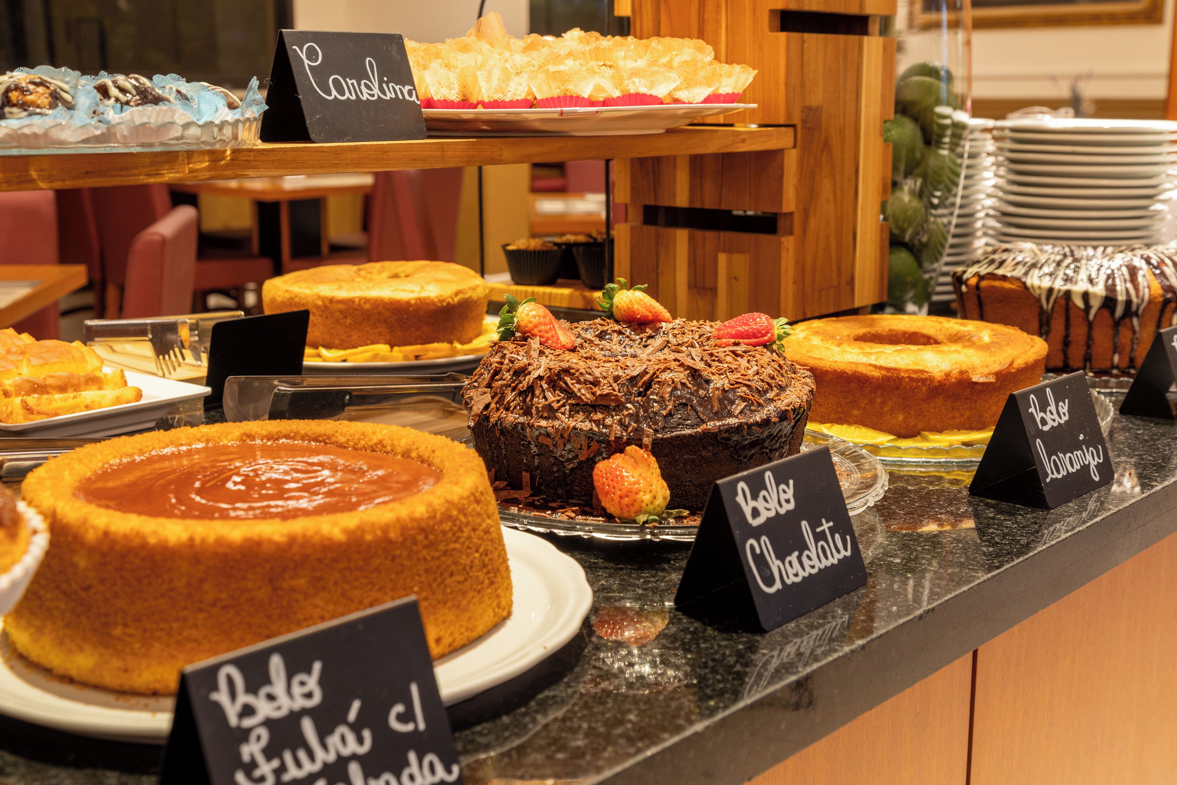 Una presentación de postres con diversos pasteles y dulces, incluyendo un pastel de chocolate con fresas.