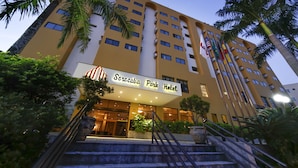 A hotel with a sign reading "Sorocaba Park Hotel," featuring a modern facade, multiple floors, and a staircase leading to the entrance.
