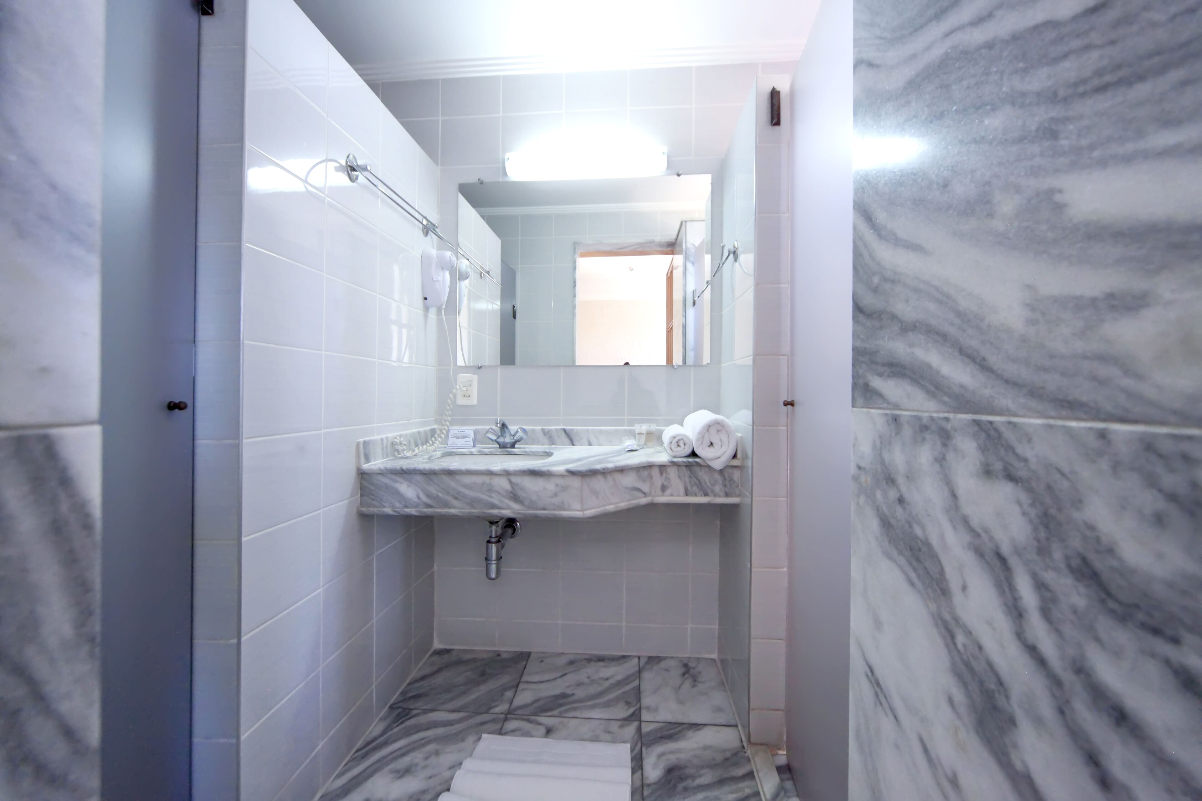 A bathroom with a marble sink, a mirror, and a shower area.