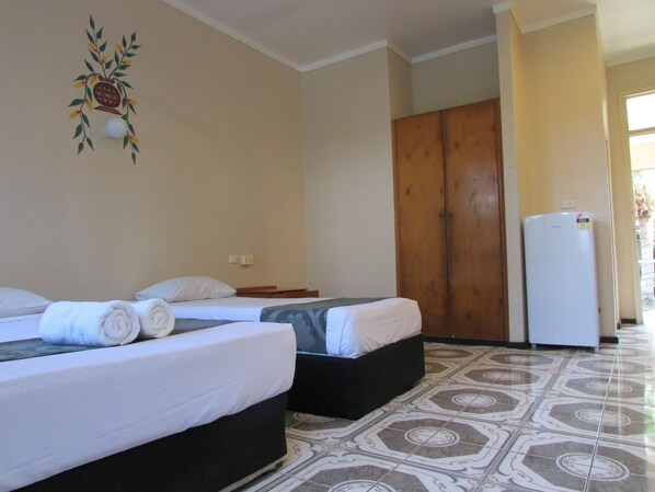 A hotel room with two beds, a wardrobe, and a refrigerator.