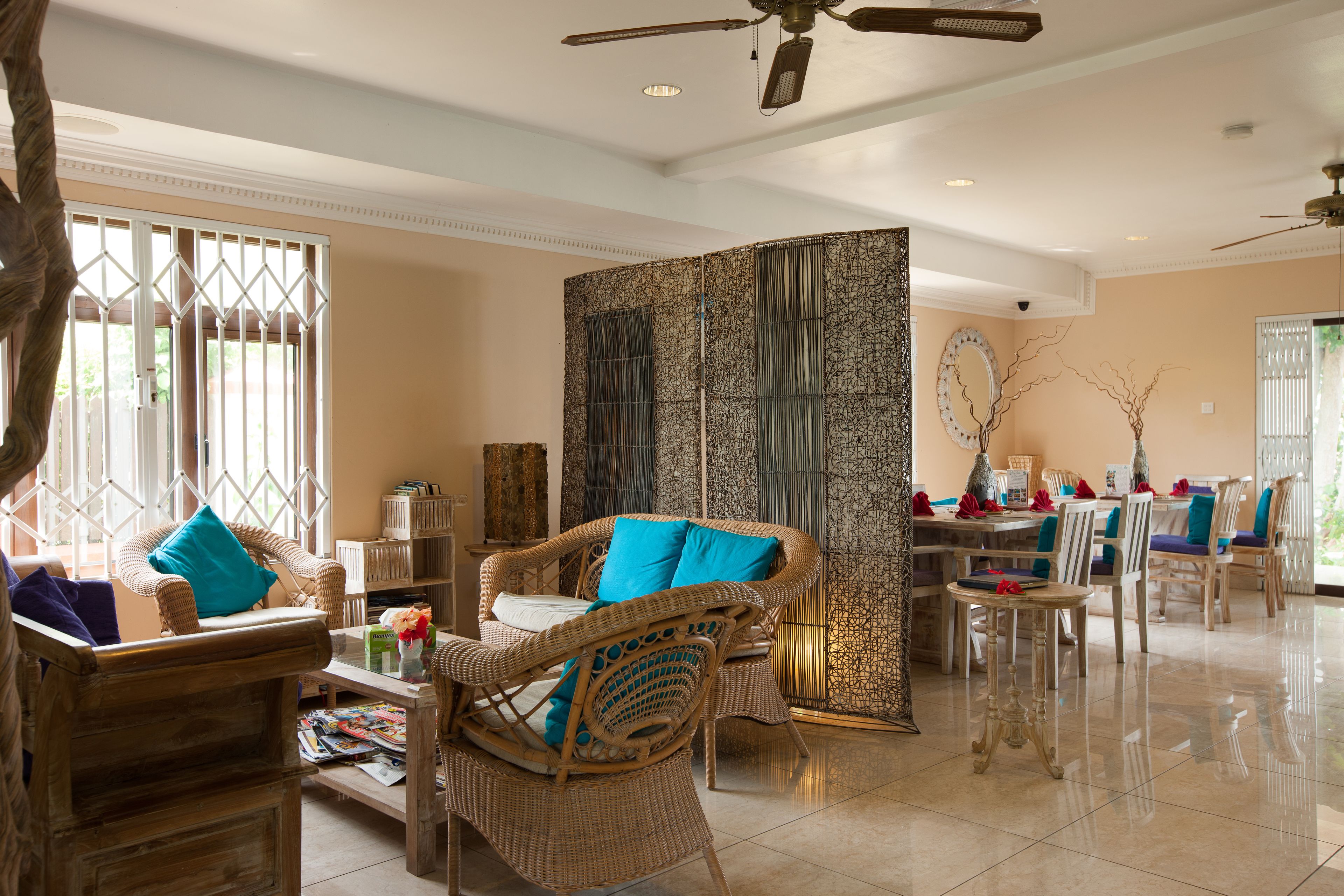 A spacious living area with wicker furniture, a dining table, and a decorative wall panel.